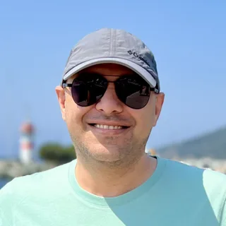 Arash Milani, smiling, on a sunny harbour front